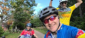 Three individuals smiling in bike riding apparel