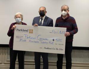 Three individuals holding large cheque