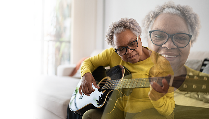 Woman sitting down and playing the guitar