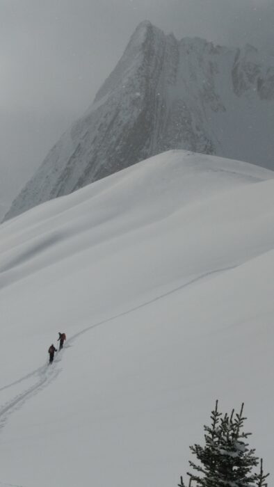 Two people walking up a snowy mountain