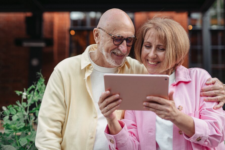 Man and woman smiling while looking at a tablet